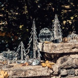 Photo of glass pumpkins at evergreen trees.