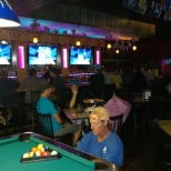 People having a good time at bar and some playing pool