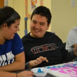 A student in the autism program works on a painting with his student aide.