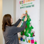 One of our Totally Team Members pins another ornament to the Totally Giving Back donation chart!