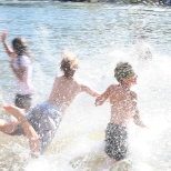 Campers splashing into the water during a hot day at camp.