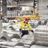 Operational employee amongst steel coils in a warehouse