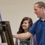 Justin Hayward, drawing and painting instructor, assists a student in class.