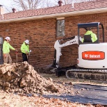 Helitech operators performing foundation repair on a home.